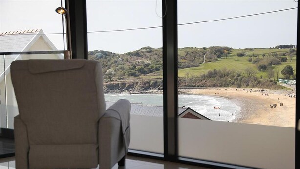A room with a large window overlooking a beach and hills. - 1 Bed in Langland (oc-hh1002) (Newton)