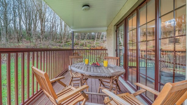 A covered outdoor deck with a table and chairs, a railing, and a view of the surrounding trees. - 3 Bed in Dailly (oc-r34760) (Dailly)