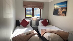 A hotel room with two beds, a window with a view, a lamp, and a painting on the wall. - 3 Bed in Dailly (oc-r34760) (Dailly)