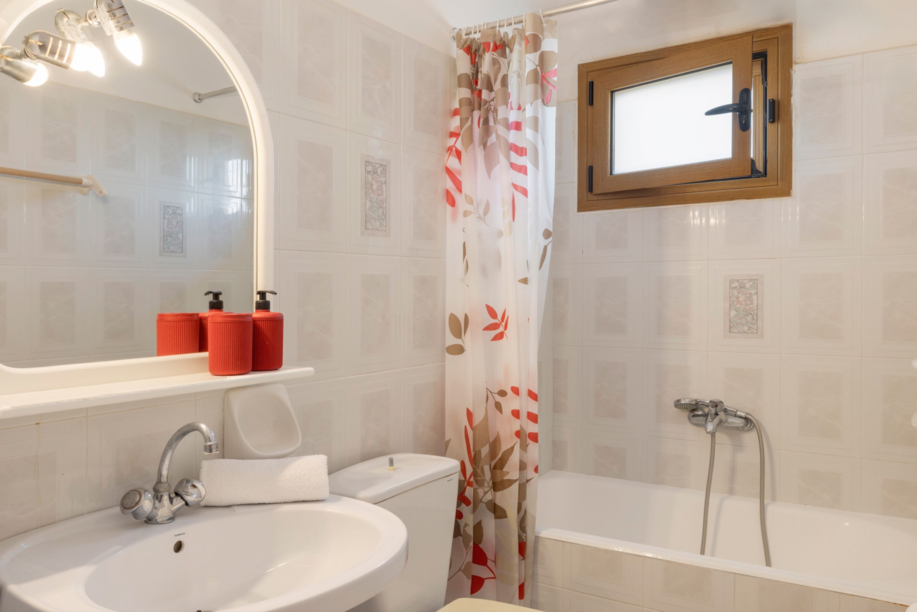 Un bagno con lavandino, WC, doccia e una finestra sopra la vasca.
