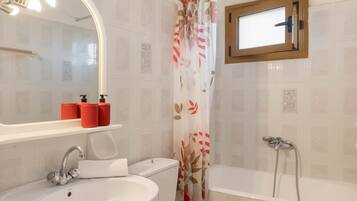 Un bagno con lavandino, WC, doccia e una finestra sopra la vasca.