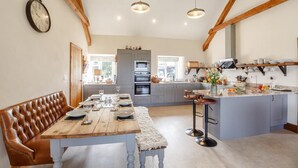 A kitchen with a central island, wooden beams, and a dining area with a bench. - 3 Bed in Llanrwst (oc-bow155) (Llanrwst)