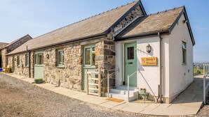 A stone building with a green door, a sign reading 'Beudy's Wennol,' and a small porch with steps. - 3 Bed in Llanrwst (oc-bow155) (Llanrwst)