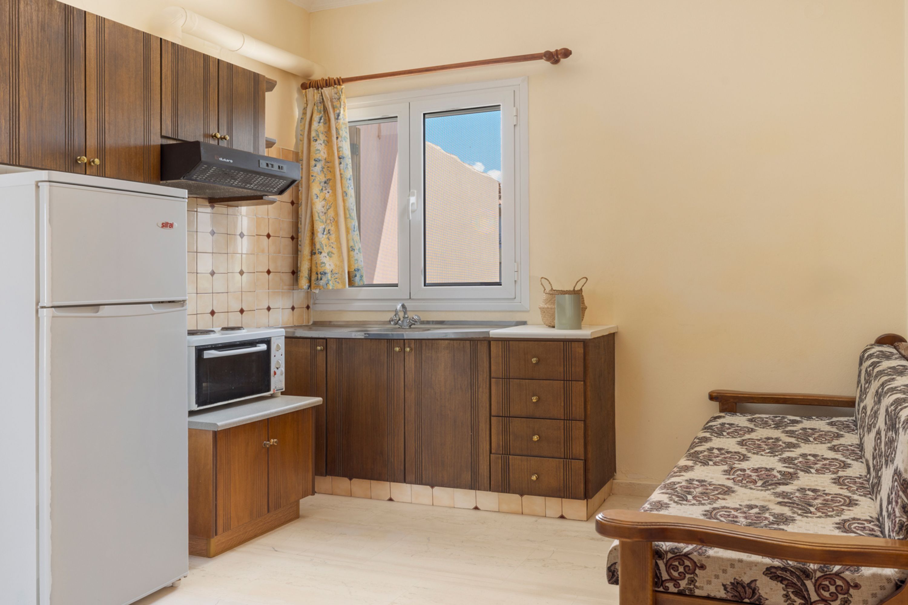 A compact kitchen with a refrigerator, microwave, and wooden cabinets.