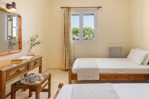 Un dormitorio con una cama de madera, una mesita de noche con espejo, una ventana con cortinas y un radiador.