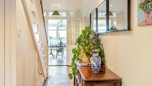 A hallway with a staircase, a dining area with a table and chairs, and a large potted plant. - 4 Bed in Galmpton (oc-h34756) (South Huish)