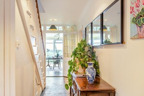 Ein Flur mit Treppe, einem Essbereich mit Tisch und Stühlen sowie einer großen Kübelpflanze.