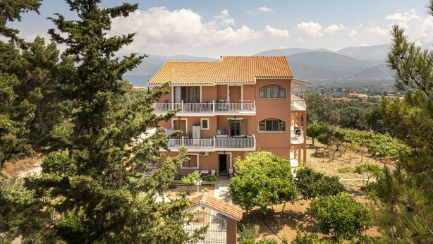 A multi-story building with balconies, surrounded by trees and mountains. - Apartment for 5 Second Building (Lakithra)