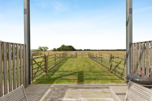 A view through a wooden gate into a grassy field with a metal structure in the distance. - 5 Bed in Walcott (oc-n34493) (Walcott)