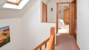 A narrow hallway with a skylight, wooden doors, a bed, and a painting. - 3 Bed in Snizort (oc-h34778) (Snizort)