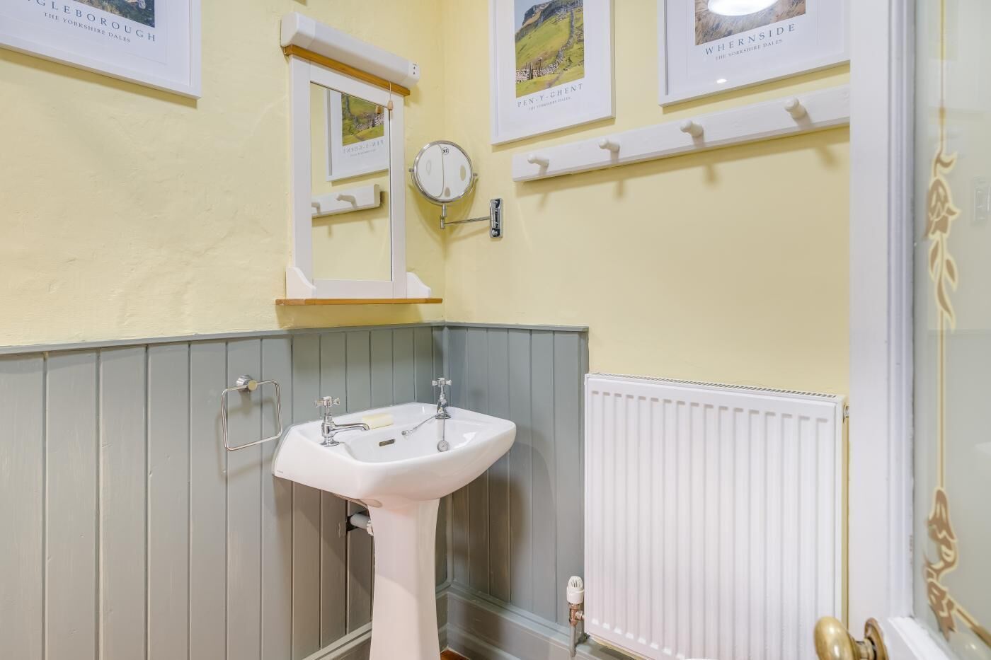 A bathroom with a white sink, a mirror, and a radiator.