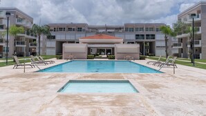 Ein modernes Hotel mit Schwimmbad, mehreren Balkonen und einer überdachten Fläche.