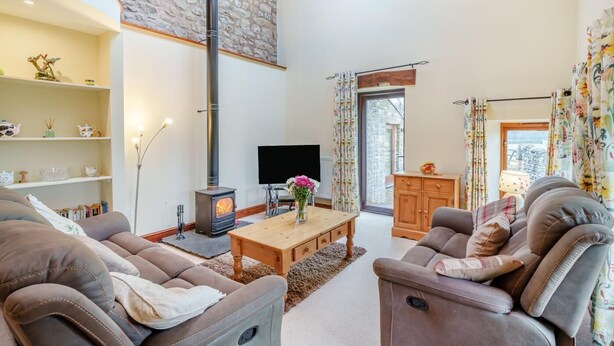 Een ruime woonkamer met een open haard, comfortabele zithoek en een televisie.