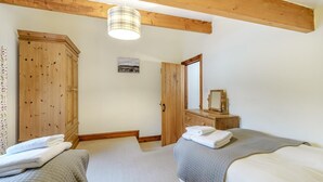 Een slaapkamer met twee bedden, een houten garderobe, een spiegel en een hanglamp.