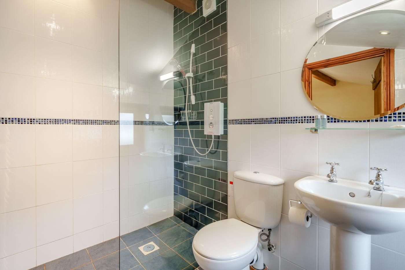 A modern bathroom with a glass shower enclosure, a toilet, and a sink with a mirror above.