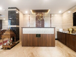 A reception desk with a marble wall, a wooden altar, and a reception sign. - Townhouse DJ Grand (Tirupati)