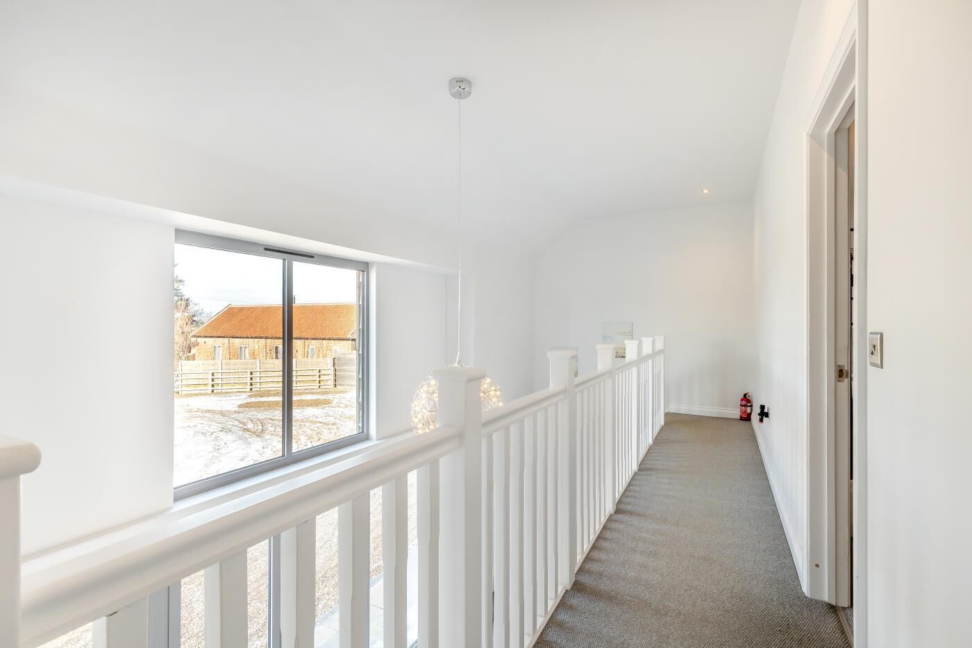 En gang med hvid gelænder, en brandslukker og udsigt til en bygning.