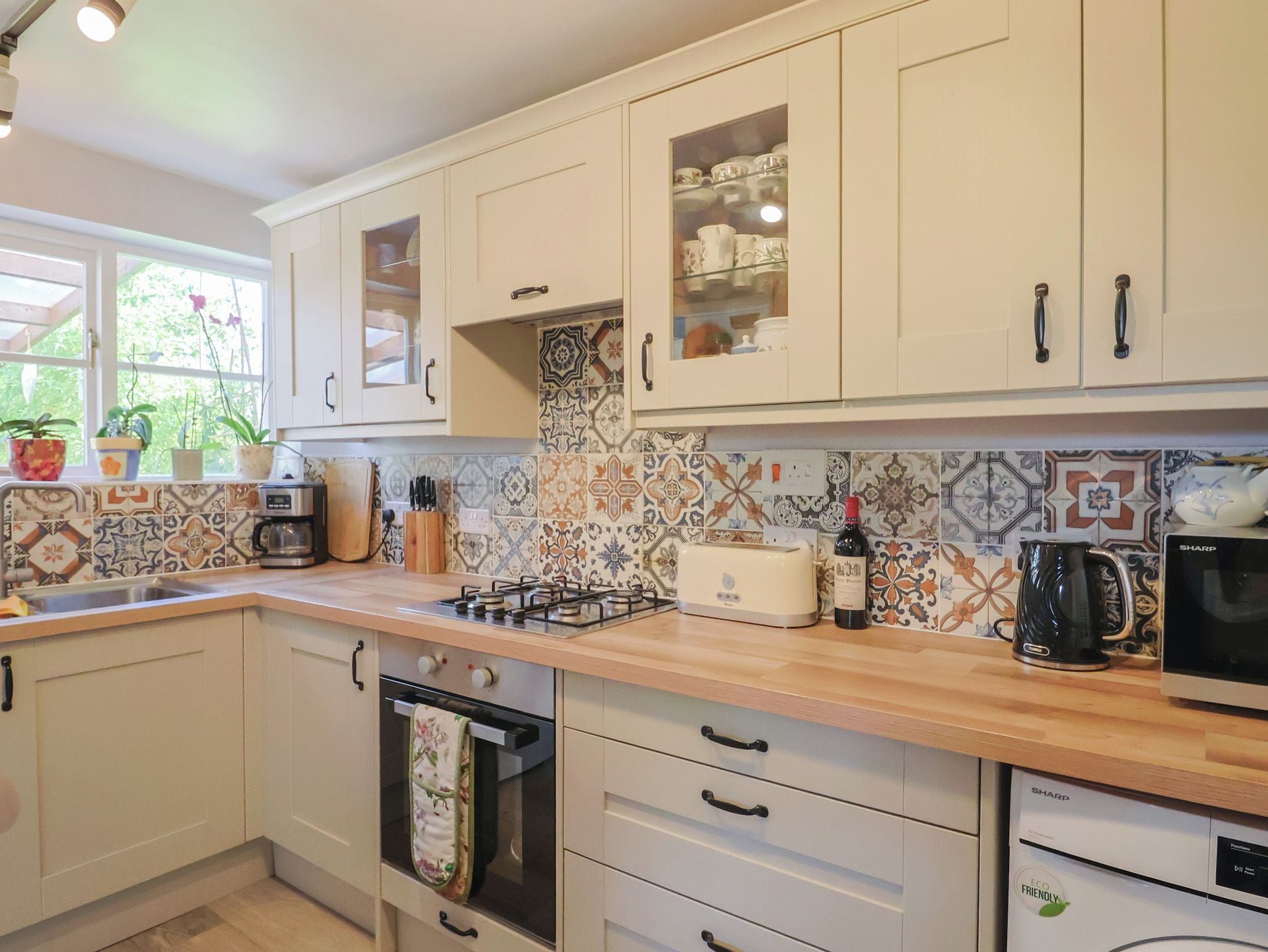 A kitchen with white cabinets, a gas stove, a toaster, a coffee maker, and a microwave.