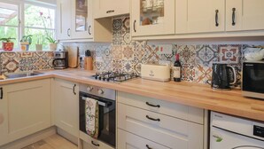 Una cocina con alacenas blancas, estufa a gas, tostadora, cafetera y microondas.