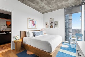 A modern bedroom with a large bed, a view of the city, and a balcony with a chair. - 2810 ATX Lux Penthouse | Rooftop Pool, Lake Views & Rainey St Nightlife (Austin)