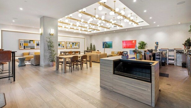 A modern hotel lobby with a dining area, a reception desk, and a large open space with ceiling lights. - Cozy Prestige Condo on Rainey | Lake Views and Rooftop Pool! (Austin)