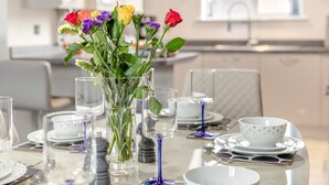 A dining table set with plates, glasses, and a vase of flowers.