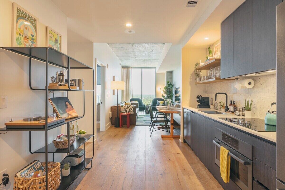 A modern kitchen with a dining area, wooden flooring, and a view to the outside.