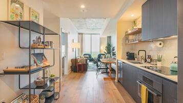 A modern kitchen with a dining area, wooden flooring, and a view to the outside.
