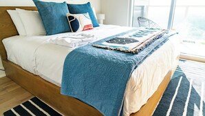 A bed with a blue quilt, white pillows, and a blue throw blanket. - King Retreat/Rooftop Views/Rainey/UT/Moody/6th St (Austin)