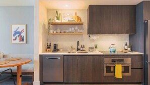 A modern kitchen with dark wood cabinets, a built-in oven, and a countertop with various kitchen items. - King Retreat/Rooftop Views/Rainey/UT/Moody/6th St (Austin)