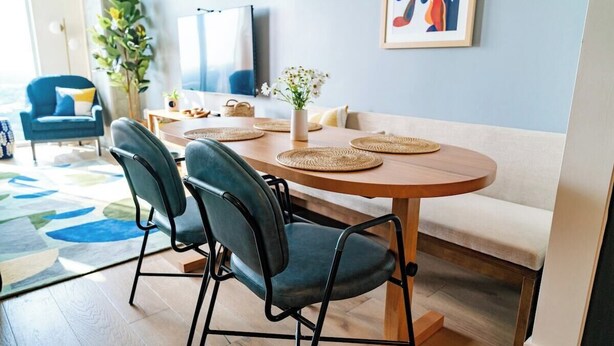 A dining area with a round table, four chairs, a vase with flowers, and a painting on the wall. - King Retreat/Rooftop Views/Rainey/UT/Moody/6th St (Austin)