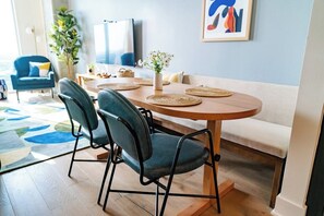 A dining area with a round table, four chairs, a vase with flowers, and a painting on the wall. - 2906 ATX Sunrise Chic | Rooftop Pool, City Views & Rainey St Nightlife (Austin)