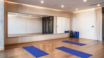 A room with a large mirror, wooden flooring, and blue mats.