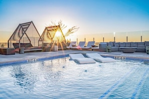 A rooftop pool with lounge chairs, a sunshade structure, and a clear view of the sunset. - 2906 ATX Sunrise Chic | Rooftop Pool, City Views & Rainey St Nightlife (Austin)