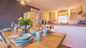 A modern kitchen with a dining table set for a meal, a refrigerator, and a washing machine. - 3 Bed in Dysart (oc-p34376) (Dysart)