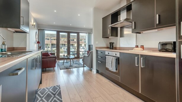 Eine moderne Küche mit Einbauofen, Mikrowelle und großem Fenster mit Blick auf einen Balkon.