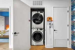 A laundry room with two stacked washing machines, a door with a decorative handle, and a wall with a floral pattern. - Modern Luxury Downtown, Mins to Everything (Austin)