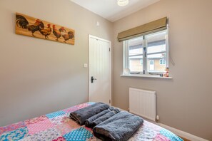 Ein Schlafzimmer mit Bett, Fenster mit Blick, Heizkörper und Tür.