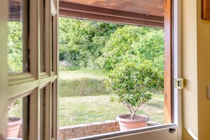 Ein Fenster mit Blick auf einen Garten, einem Blumentopf und einer Ziegelmauer.