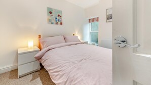 Ein Schlafzimmer mit Bett, Nachttischen, einem Fenster und Bildern an den Wänden.