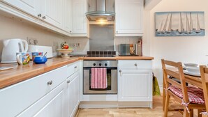 Eine kompakte Küche mit weißen Schränken, einem Edelstahlbackofen, einer Mikrowelle und einer Holz Arbeitsplatte.