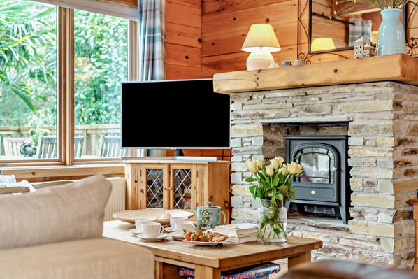 A cozy living room with a stone fireplace, a television, and a dining area with a table set for two.
