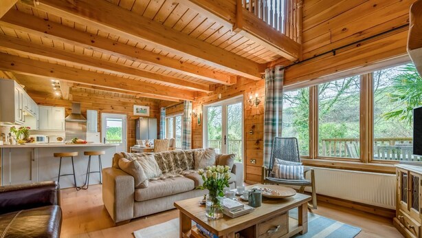 Interior de uma cabana de madeira com sofá, mesa de centro e área de refeições.