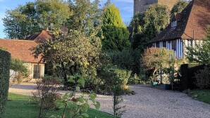 Ein Innenhof mit Kiesweg, einem kleinen Baum und einer Steinmauer.