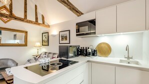 Eine moderne Küche mit einer zentralen Kochinsel, integrierten Geräten und einem Holzbalken an der Decke.