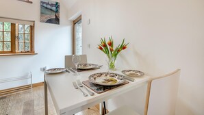 Ein Esstisch ist gedeckt mit Tellern, Besteck und einem Glas, und darauf steht eine Vase mit Tulpen.