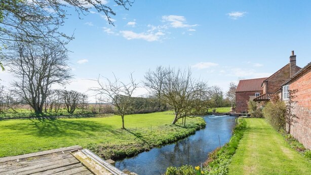A riverside property with a wooden dock, a brick house, and a grassy area. - 2 Bed in Kirkby Green (oc-s34761) (Kirkby Green)