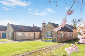 A rural setting with stone buildings, a grassy area, and a railway track.