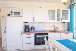 A compact kitchen with white cabinets, a built-in oven, a coffee maker, and a sink. - Stilvolle Ferienwohnung mit Gemutlichem Balkon in Sellin (Sellin)