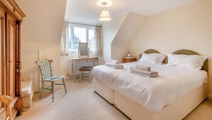 Ein Schlafzimmer mit Bett, Schreibtisch, Stuhl und Fenster.
